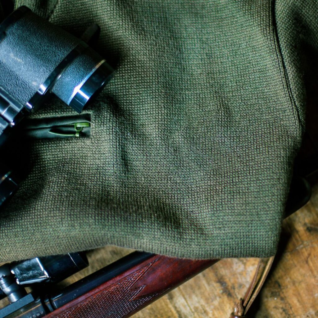 rifle, binoculars and hunter green sweater