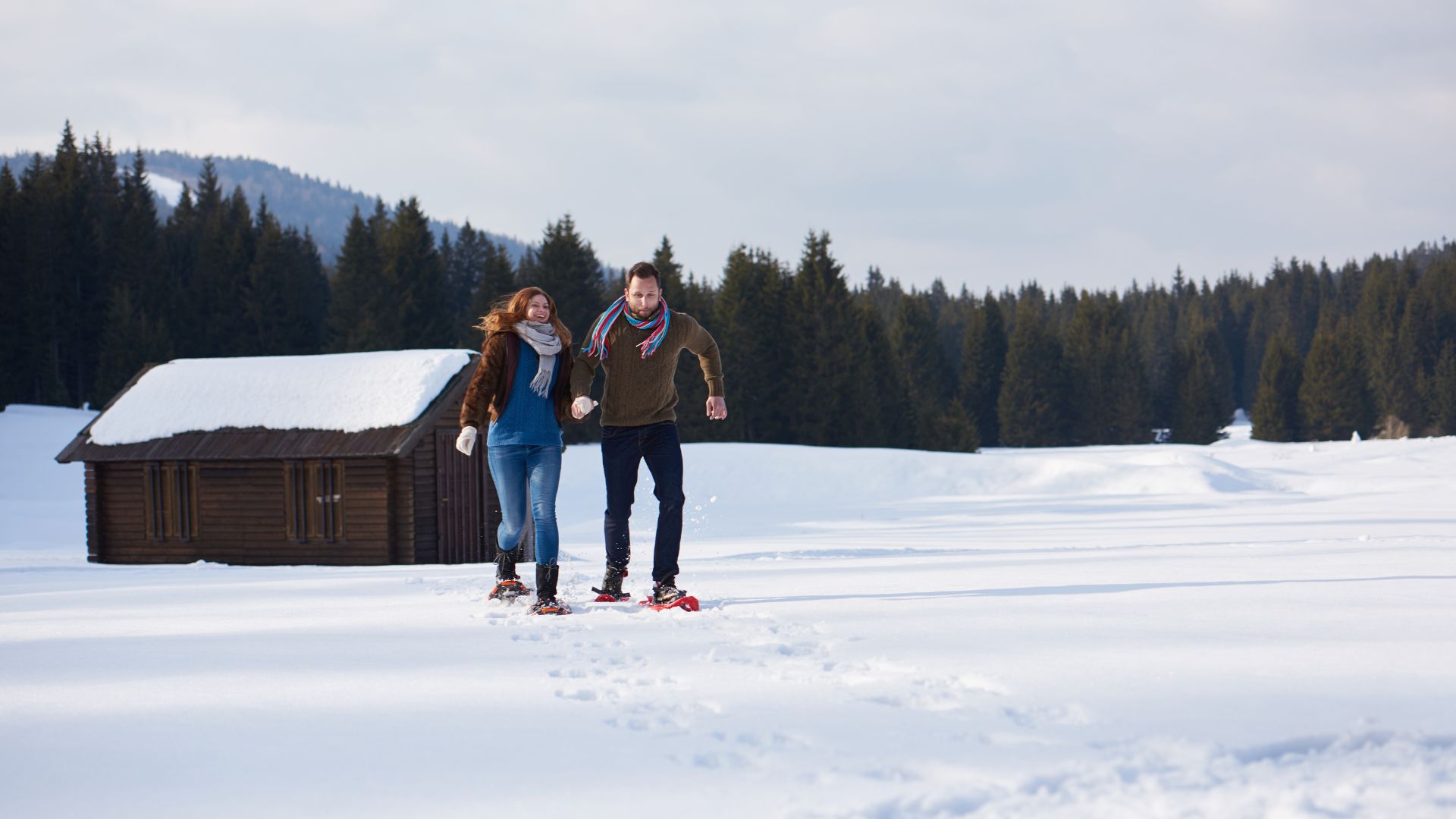 couple smiling walking in snow field with snowshoes